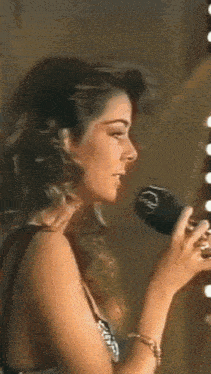 a woman is singing into a microphone with the letter r on it .