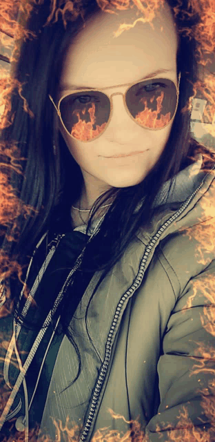 a woman wearing sunglasses with fire reflections in her eyes