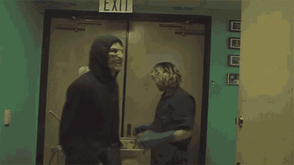 a person wearing a black hoodie is standing in front of a mirror .