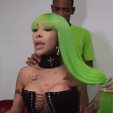 a woman with green hair has a tattoo on her chest that says " ego "