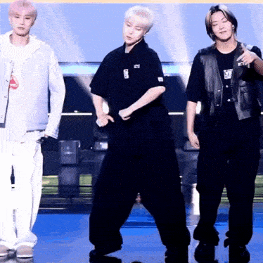 a group of young men are dancing on a stage and one of them is wearing a shirt that says ' nct '