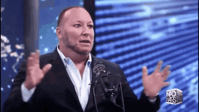 a man in a suit and white shirt is speaking into a microphone with the words fox news wars behind him