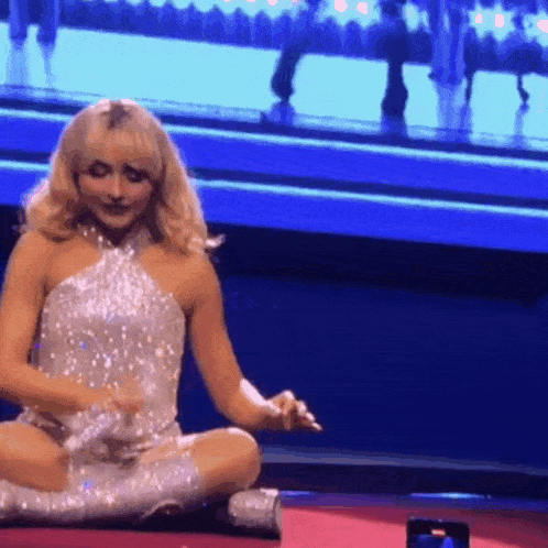 a woman in a sequined dress sits on the floor