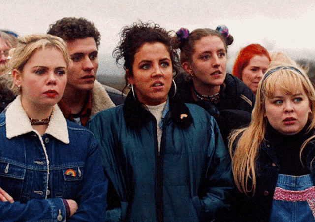 a woman in a blue jacket has a rainbow patch on her collar