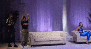 a woman in a black shirt that says power is dancing in front of a couch
