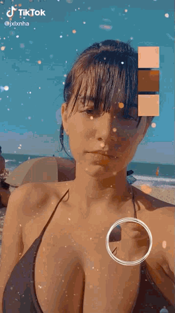 a woman in a bikini is taking a picture of herself on the beach .