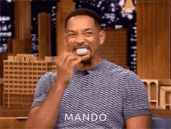 will smith is laughing while holding a piece of food in his hand .