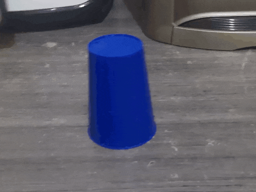 a blue cup with a face and arms is standing next to a white cylinder