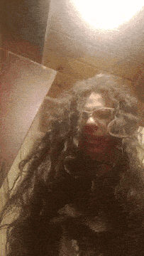 a woman wearing glasses and a wig is smiling for the camera