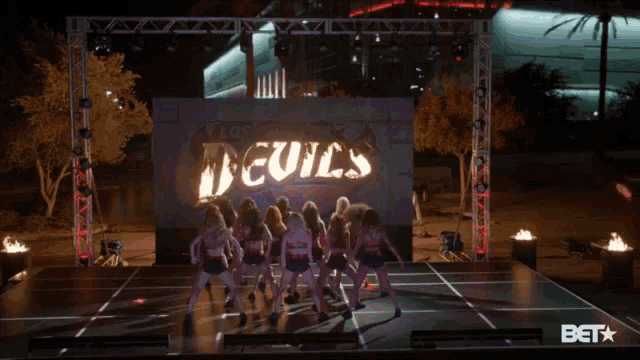 a group of dancers are performing on a stage in front of a sign that says deuce 's