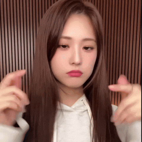 a young woman with long brown hair is making a funny face while wearing a white hoodie .