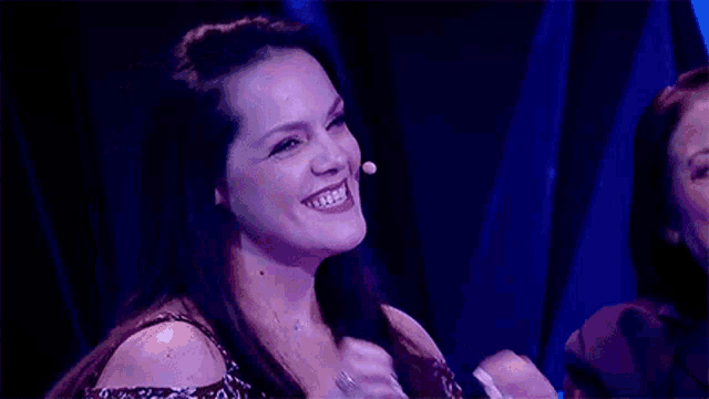 a woman is laughing while sitting in front of a microphone .