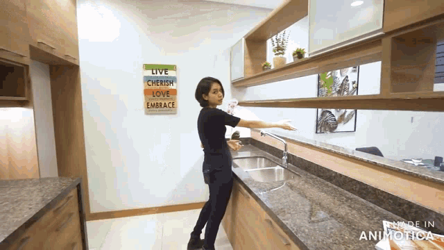 a woman in a kitchen with a sign that says " live cherish love embrace "
