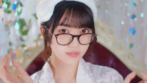 a woman wearing glasses and a white headband looks at the camera