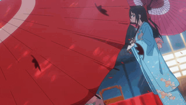 a woman in a blue kimono holds a red umbrella