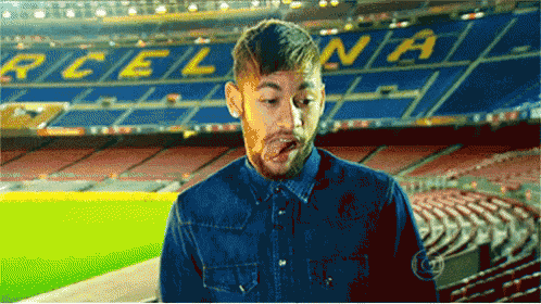 a man sticking his tongue out in front of a stadium that says ' barcelona ' on it