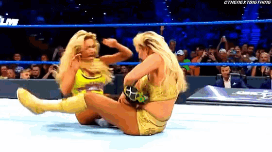 two women are wrestling in a ring and one of them is wearing yellow shorts