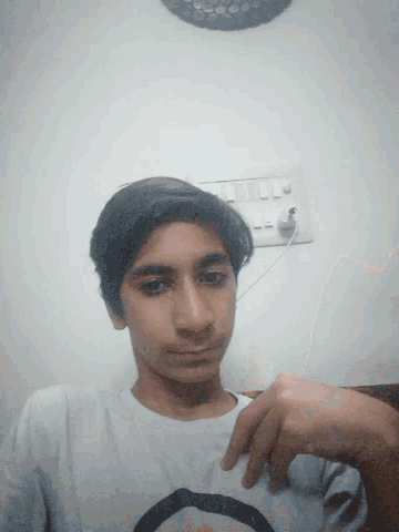 a young man wearing a white shirt with a black circle on the front