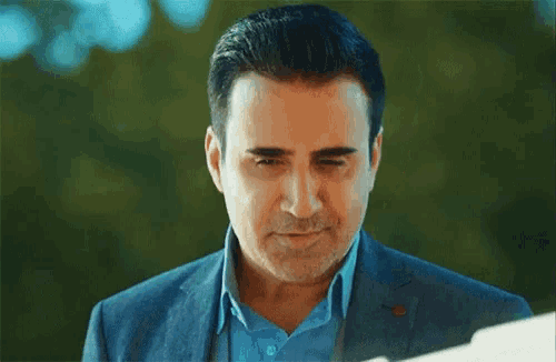 a man in a suit and blue shirt is smiling and looking down