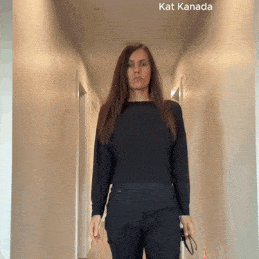 a woman in a black shirt is standing in a hallway with kat kanada written on the bottom