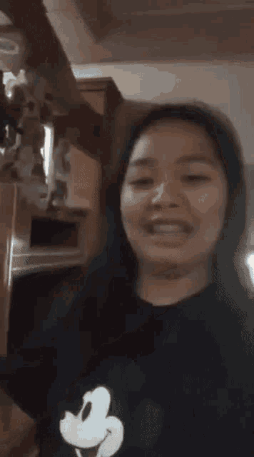 a woman wearing a mickey mouse t-shirt is smiling