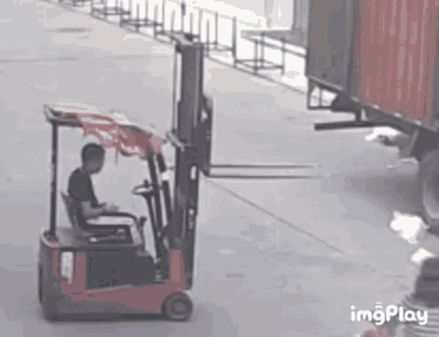 a man is driving a forklift in a parking lot .