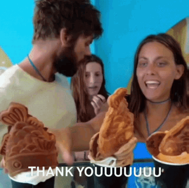 a man and a woman are holding fish shaped waffles and the woman is saying thank you