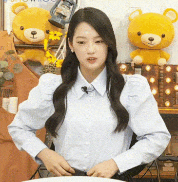 a woman in a blue shirt is standing in front of stuffed teddy bears and a sign that says " gift your "