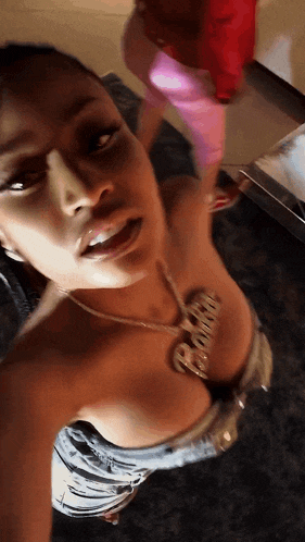 a woman taking a selfie with a necklace that says ' gucci ' on it