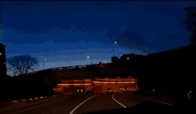 a car is driving down a highway at night with a blue sky in the background