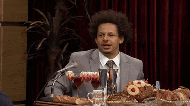 a man in a suit and tie is sitting at a table with food