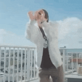 a man is standing on a balcony with his hands in the air and making a funny face .