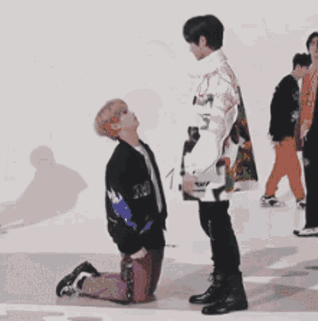 a man in a jacket with the number 1 on it is kneeling down next to another man