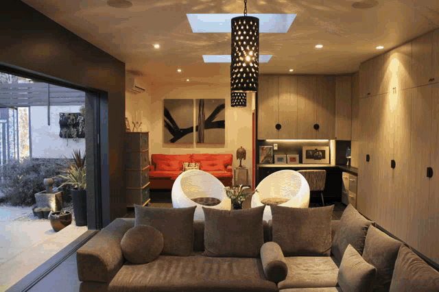 a living room with a couch and chairs and a skylight above