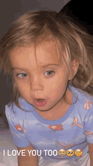 a little girl wearing a blue shirt that says i love you too on it