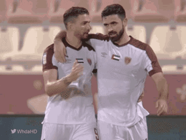 two soccer players are hugging each other in a stadium