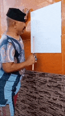 a man is holding a piece of paper in front of a wall .