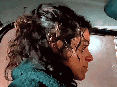 a close up of a person 's face with curly hair .