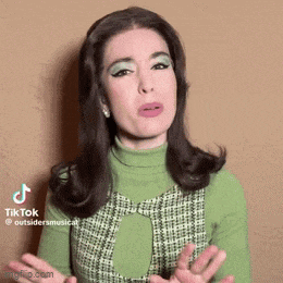 a woman in a green dress is making a funny face with her hands outstretched .