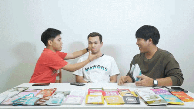 a man wearing a shirt that says wkndrs is being touched by two other men