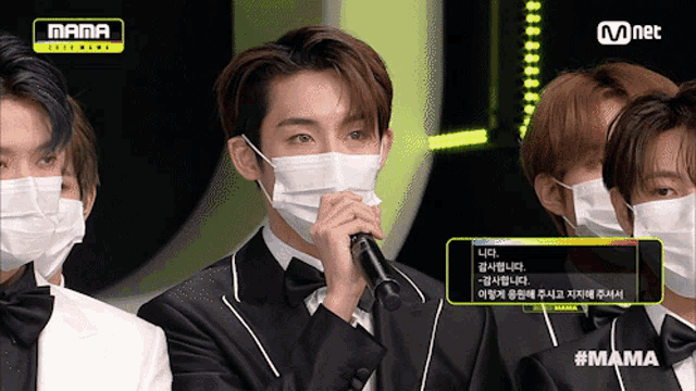 a group of men wearing face masks with a mnet logo in the background