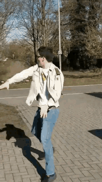 a man is dancing on a brick sidewalk in front of trees