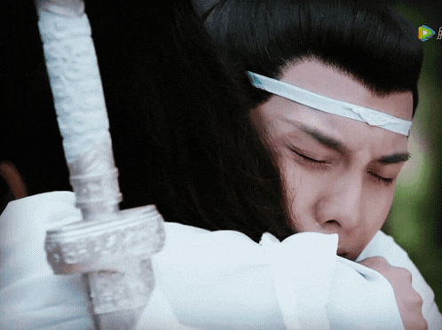a man is hugging another man with a sword behind him