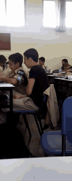 a boy in a black shirt is sitting in a classroom