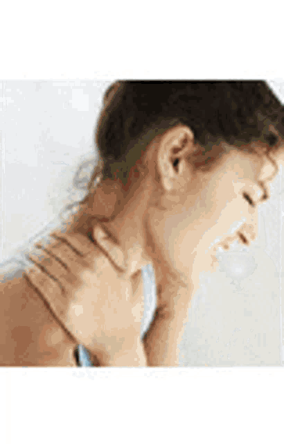 the woman is holding her neck in pain .