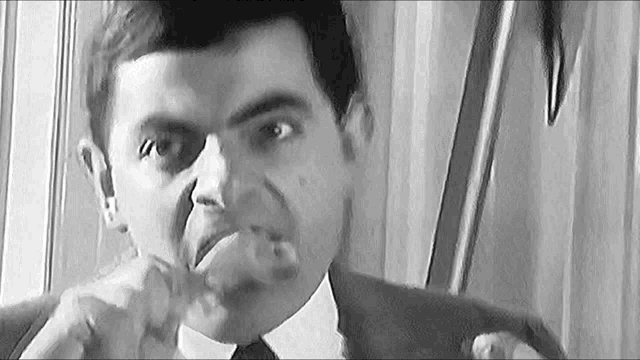 a black and white photo of a man in a suit and tie making a face .