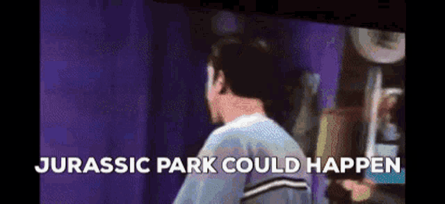 a man is standing in front of a screen with the words jurassic park could happen written above him .