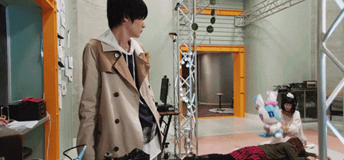 a man in a trench coat is standing in a room with a stuffed animal laying on the floor