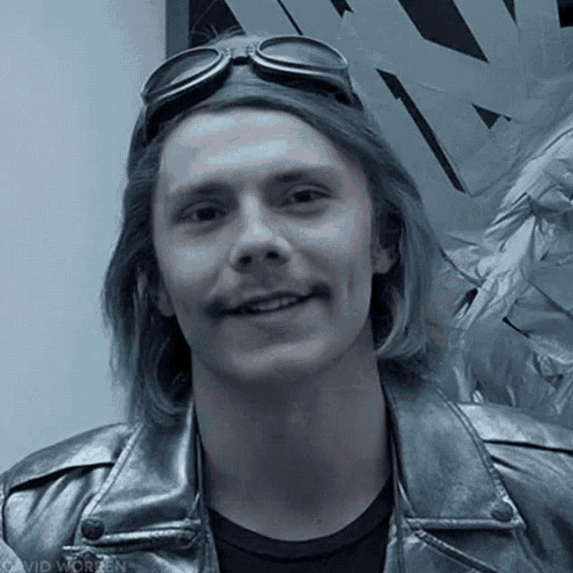 a man wearing a silver jacket and goggles is smiling for the camera
