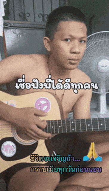 a shirtless man is playing a guitar in a room